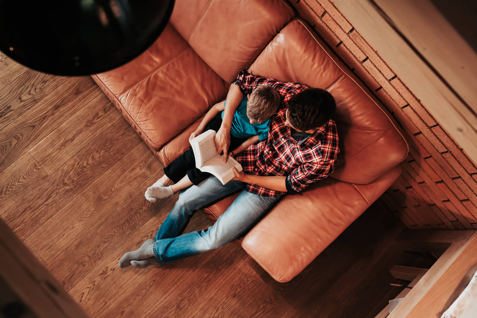 A father and son reading together on the couch